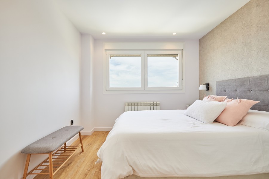 dormitorio reformado con diseño moderno, paredes claras y suelo de madera en Madrid